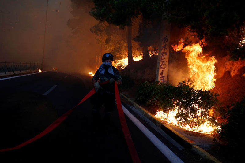 © Reuters. Soldado diante de incêndio na cidade de Rafina, perto de Atenas