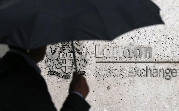 © Reuters. FILE PHOTO - A man shelters under an umbrella as he walks past the London Stock Exchange