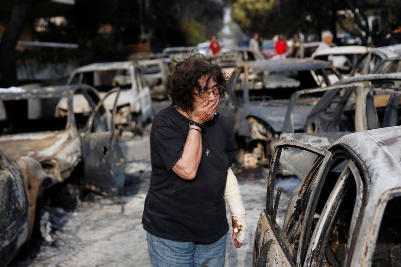 © Reuters. Mulher tenta encontrar seu cachorro após incêndio em Mati, perto de Atenas