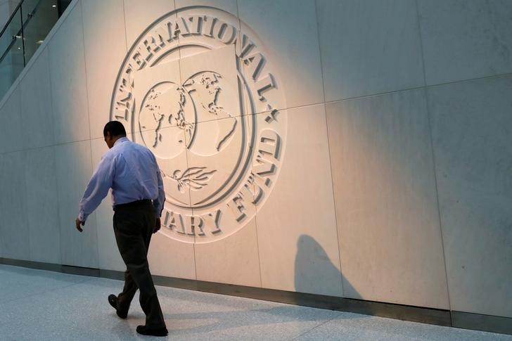 © Reuters. Man walks past the IMF logo at HQ in Washington