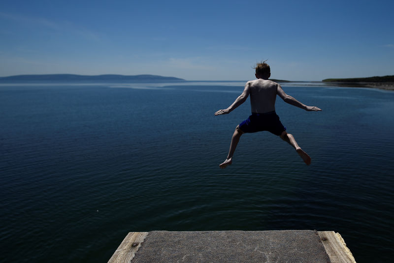 © Reuters. A man jumps off a diving board on Salthill beach during sunny weather in Galway