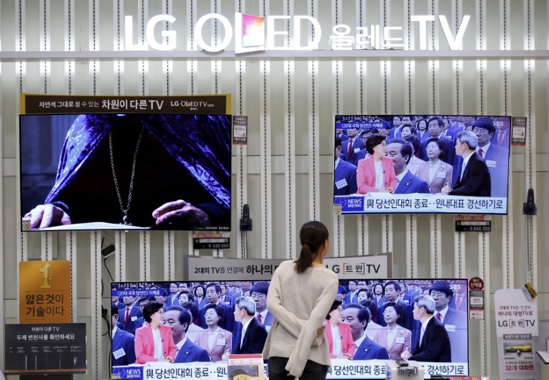 © Reuters. FILE PHOTO: A woman looks at a LG Electronics' organic light-emitting diode (OLED) TV sets, which are made with LG Display flat screens, at its store in Seoul
