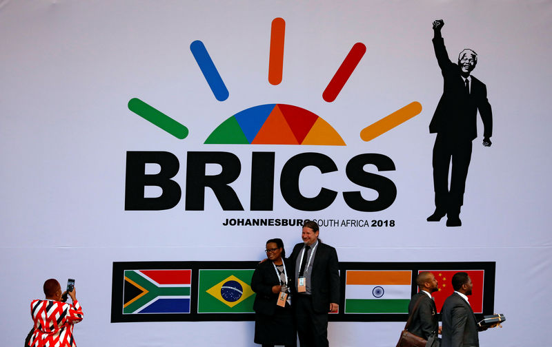 © Reuters. Delegates take pictures beneath a billboard outside the BRICS summit meeting in Johannesburg