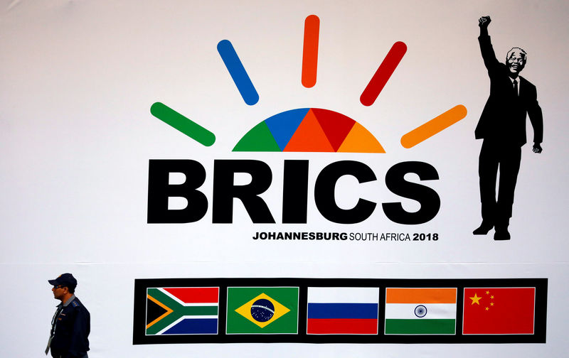 © Reuters. A police officer walks past a billboard outside the BRICS summit meeting in Johannesburg