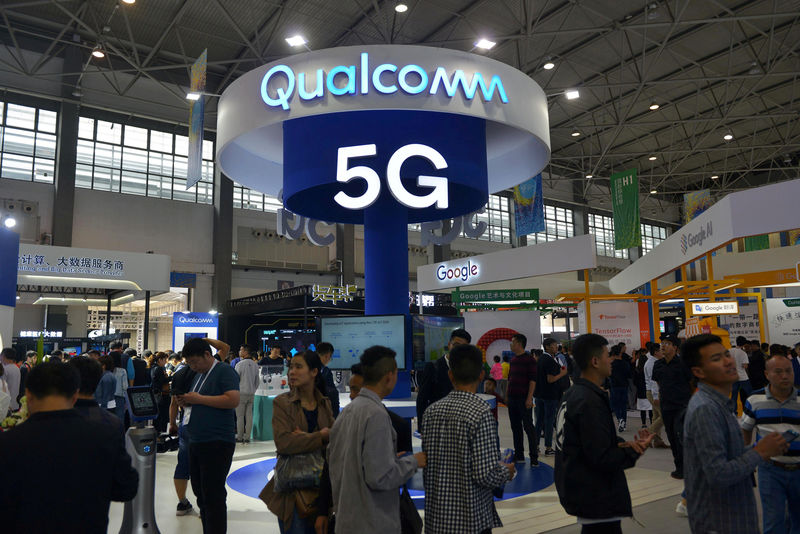 © Reuters. FILE PHOTO: Visitors are seen by a booth of Qualcomm Inc at the China International Big Data Industry Expo in Guiyang