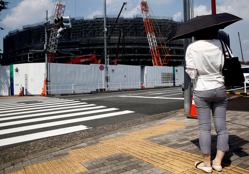 © Reuters. FILE PHOTO: A woman holding a parasol stands in front of the construction site of the New National Stadium, the main stadium of the Tokyo 2020 Olympics and Paralympic in Tokyo