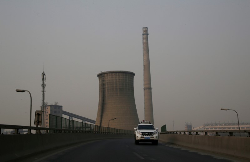 © Reuters. A vehicle drives past a closed factory on a polluted day in Beijing