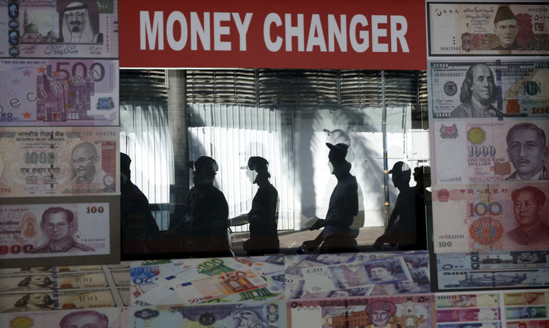 © Reuters. FILE PHOTO: Pedestrians are reflected in a money changer's screen in Kuala Lumpur, Malaysia