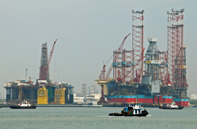 © Reuters. FILE PHOTO: Tugboats pass jack-up rigs at a Keppel FELS shipyard in Singapore