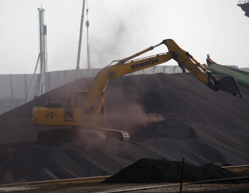 © Reuters. A bulldozer and a labor work on a pile of iron ore at a steel factory in Tangshan in China's Hebei Province