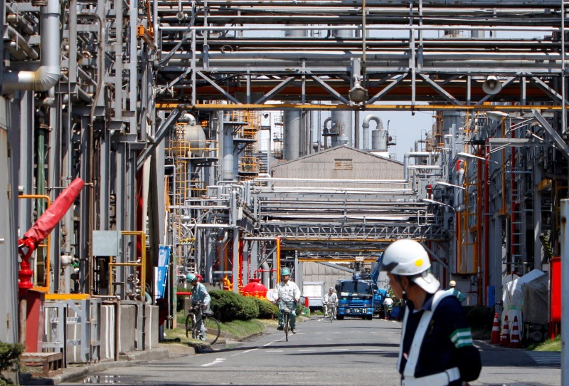 © Reuters. FILE PHOTO: Workers ride bicycles as a guard looks on at a factory in Keihin industrial zone in Kawasaki