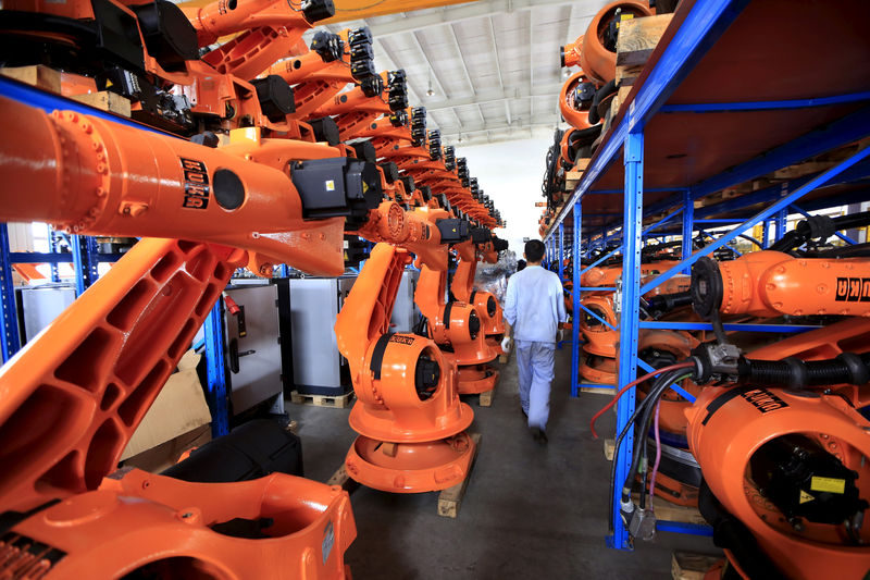 © Reuters. FILE PHOTO: A worker walks past second-hand robots in a factory in Shanghai