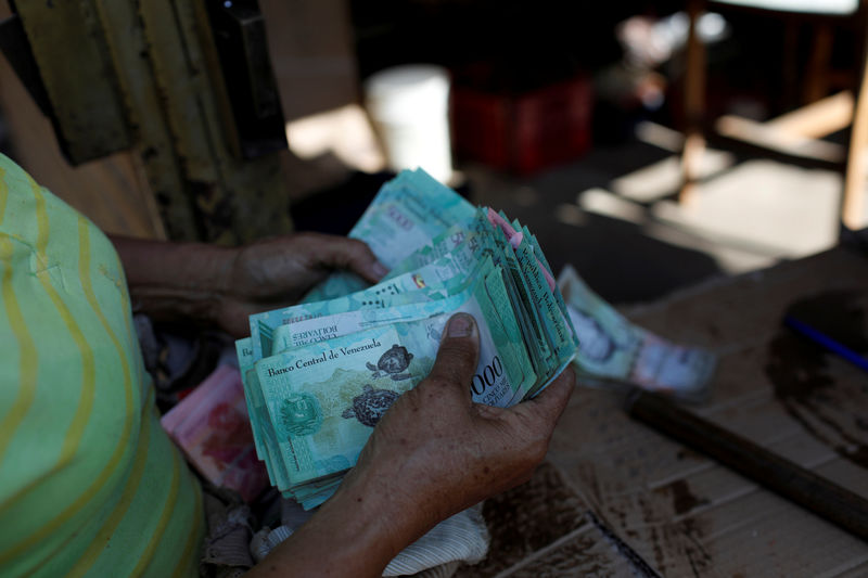 © Reuters. FILE PHOTO: A woman counts Venezuelan bolivar notes in her stall at Las Pulgas market in Maracaibo