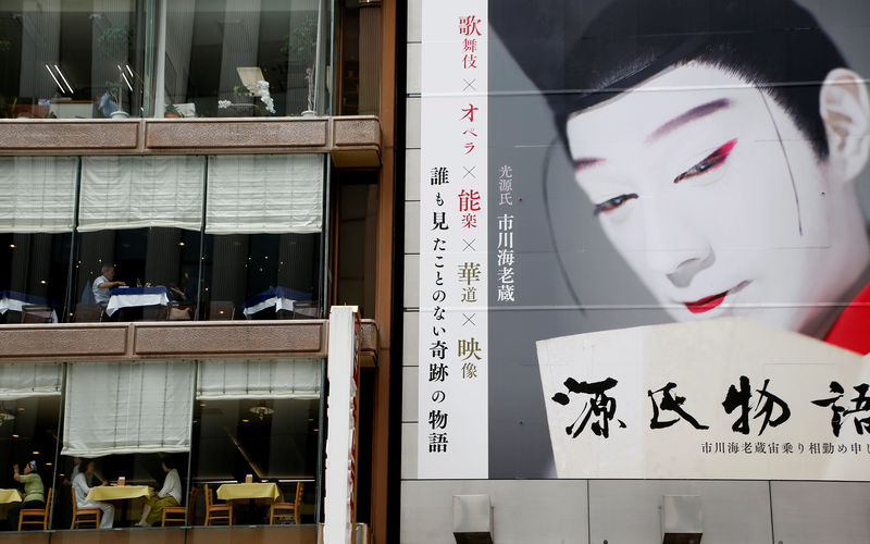 © Reuters. Customers have lunch at restaurants next to a record shop which has a large poster on its wall in Tokyo, Japan