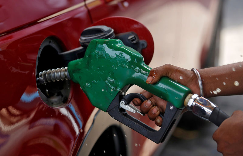 © Reuters. FILE PHOTO: A worker holds a nozzle to pump petrol into a vehicle at a fuel station in Mumbai