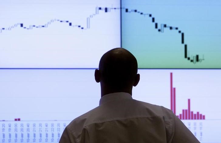 © Reuters. Сотрудник фондовой биржи перед экраном с графиками