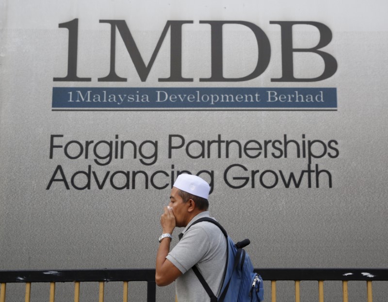 © Reuters. FILE PHOTO: A man covers his mouth as he walks past a 1 Malaysia Development Berhad (1MDB) billboard at the funds flagship Tun Razak Exchange development in Kuala Lumpur, Malaysia