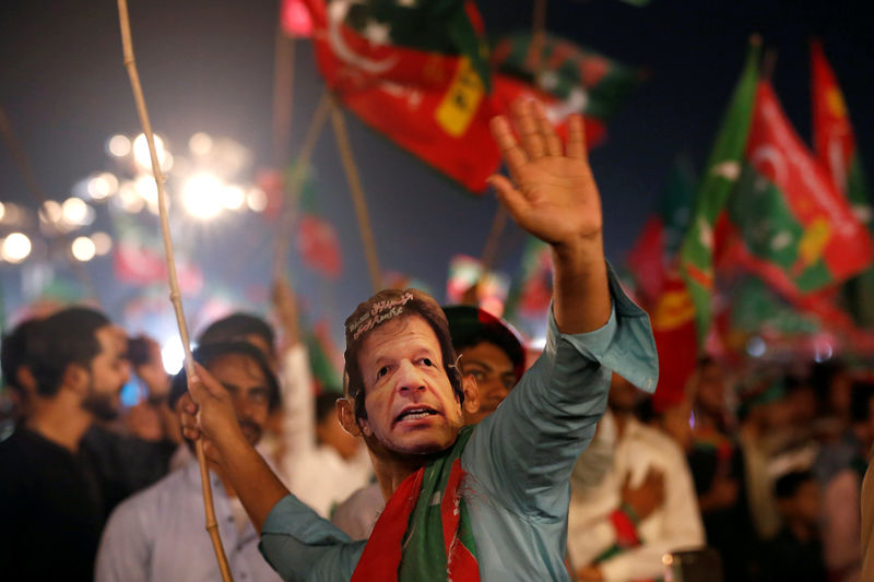 © Reuters. FILE PHOTO: A supporter of Imran Khan, chairman of the PTI, political party, wears a mask and dance on party songs during a campaign rally ahead of general elections in Karachi