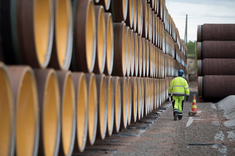 © Reuters. FILE PHOTO: A man walks by a stack of North Stream 2 pipes in Kotka