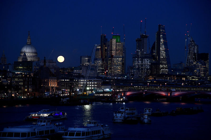© Reuters. FILE PHOTO: A full moon rises behind The City of London