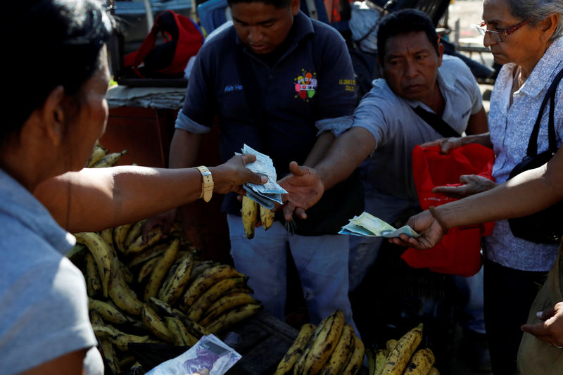 © Reuters. FILE PHOTO: A vendor receives Venezuelan bolivar notes in her stall at Las Pulgas market in Maracaibo