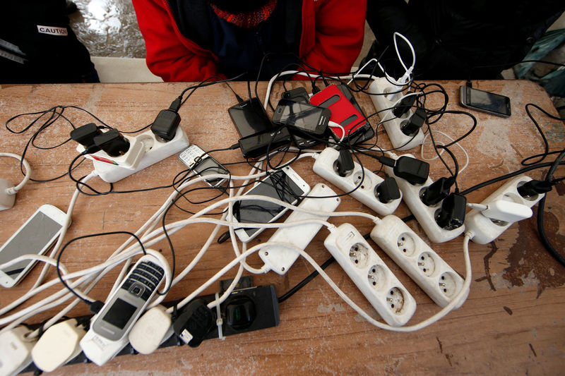 © Reuters. FILE PHOTO: Migrants charge their mobile phones with a generator at the Calais refugee camp