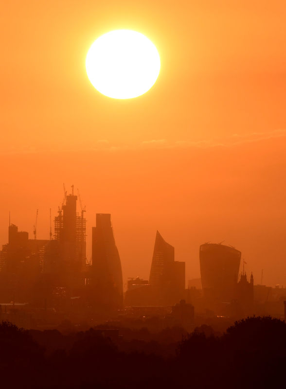 © Reuters. FILE PHOTO: The sun rises behind skyscrapers in the City of London in London, Britain