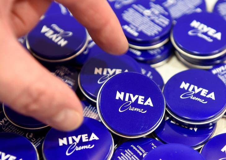 © Reuters. FILE PHOTO A shareholder of German care cosmetic company Beiersdorf picks up a Nivea tin before the start of the shareholder meeting in Hamburg
