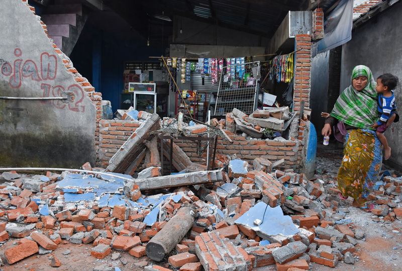 © Reuters. Mulher passa por destroços de parede destruída por forte terremoto em Lombok, na Indonésia