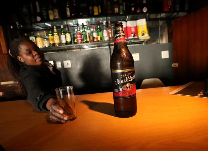 © Reuters. A woman serves a one litre bottle of AB Inbev's Carling Balck Label beer at a bar in Cape Town
