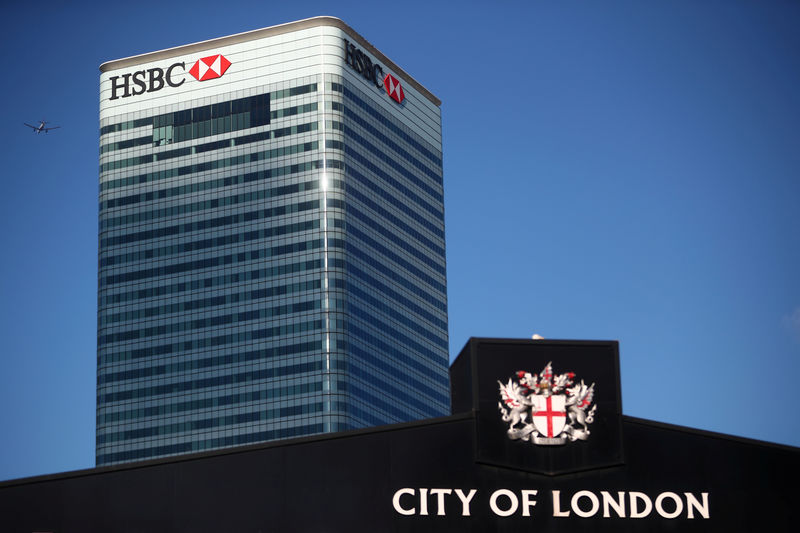 © Reuters. FILE PHOTO: HSBC's building in Canary Wharf is seen behind a City of London sign