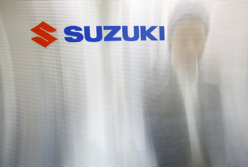 © Reuters. FILE PHOTO: A man is seen through a compartment board with the logo of Suzuki Motor seen on it at the company's showroom in Tokyo