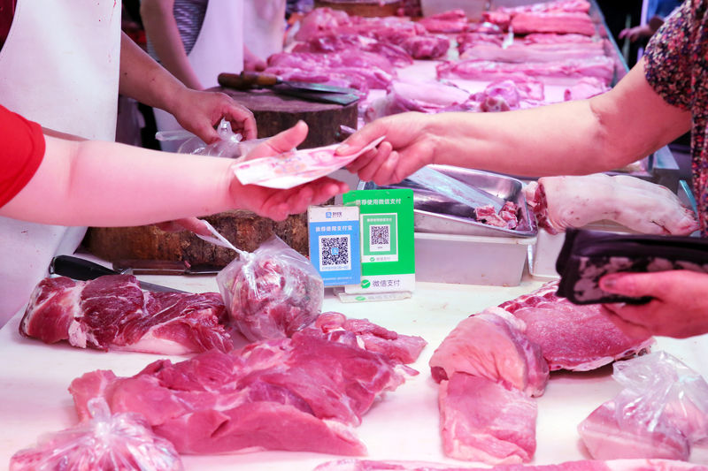 © Reuters. Customer pays cash at a pork stall inside a market in Nantong