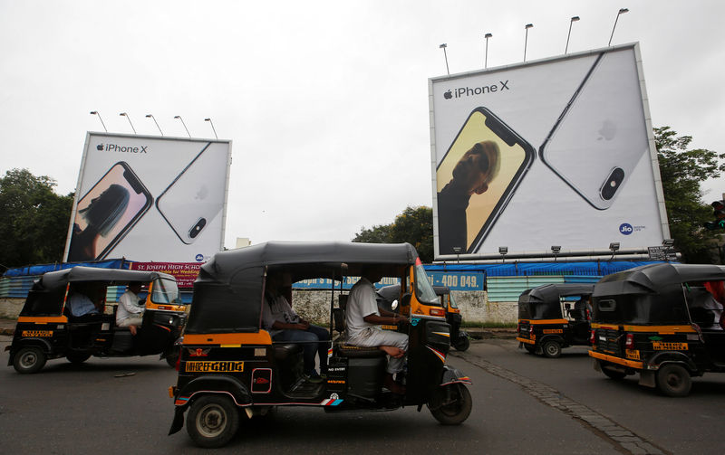 © Reuters. FILE PHOTO: Auto-rickshaws drive past the hoardings of Apple iPhone X mobile phones in Mumbai