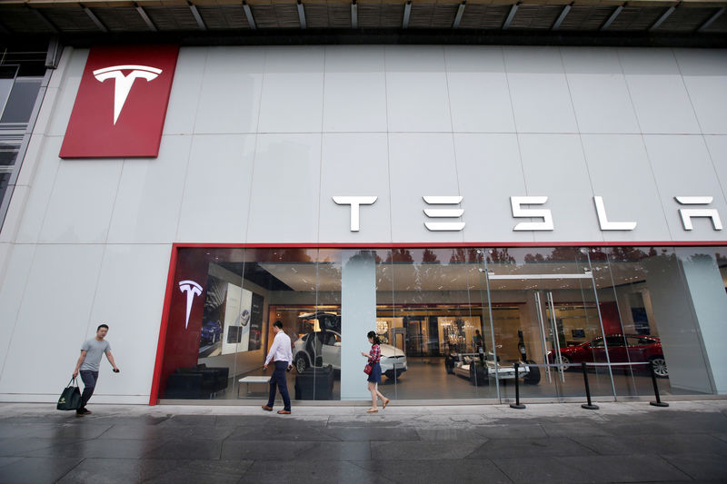 © Reuters. FILE PHOTO: People walk past a showroom outside Tesla China headquarters in Beijing