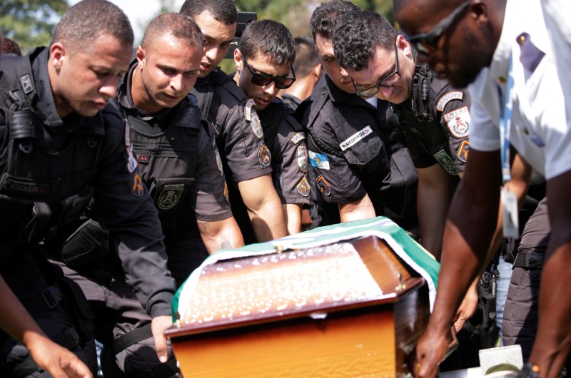 © Reuters. Policiais carregam caixão de colega morto em confronto na favela da Rocinha