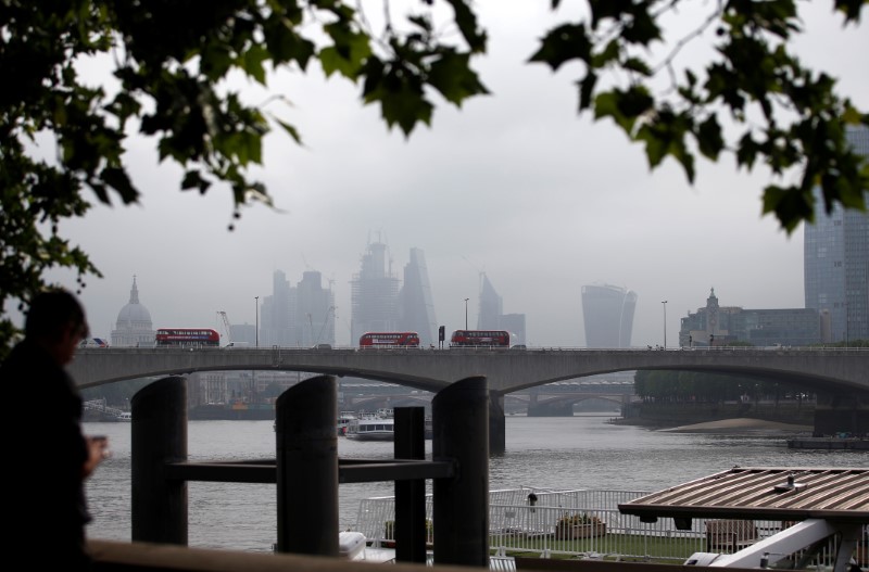© Reuters. A traditional red London bus crosses Waterloo Bridge, with the financial district in the background, in London