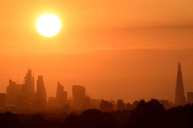 © Reuters. The sun rises behind skyscrapers in the City of London in London, Britain