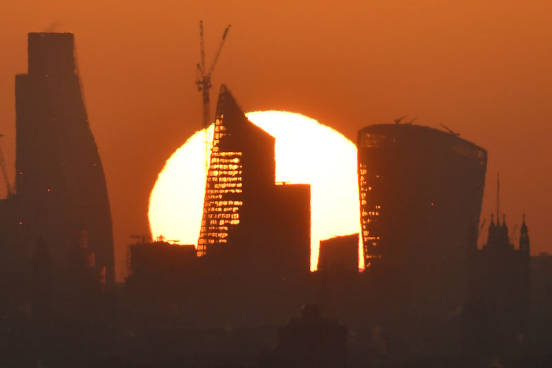 © Reuters. FILE PHOTO: The sun is seen rising over skyscrapers in the City of London financial district in London