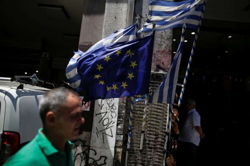 © Reuters. FILE PHOTO: Greek national flags and a European Union flag flutter outside a shop in central Athens