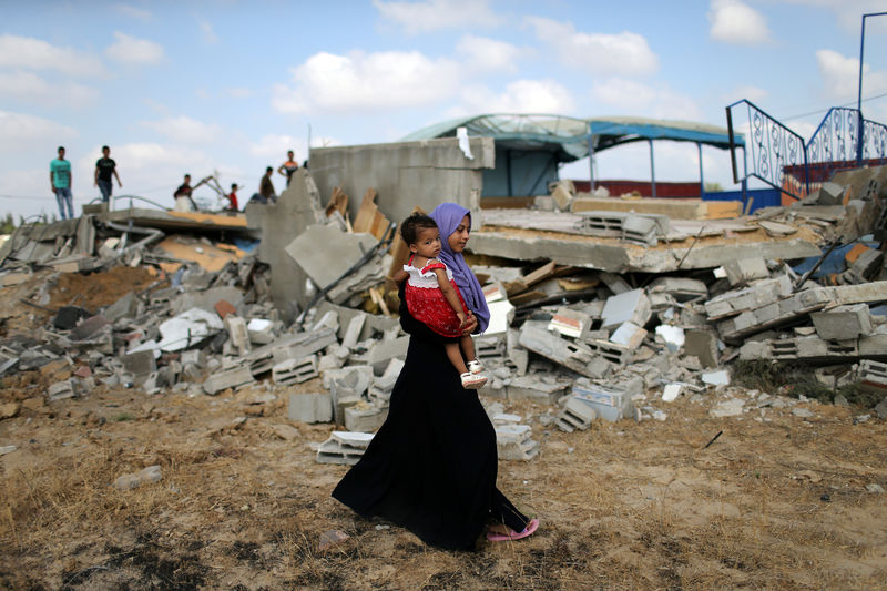 © Reuters. Palestina leva menina no colo em local de ataque israelense em Khan Younis, na Faixa de Gaza