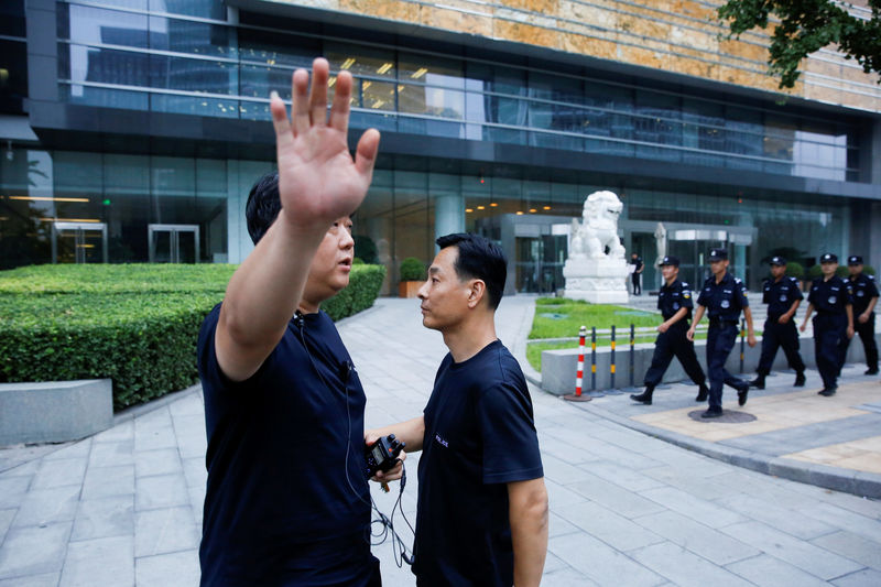 © Reuters. FILE PHOTO: A police officer gestures at the photographer as security patrol outside the headquarters of China's banking regulator in Beijing