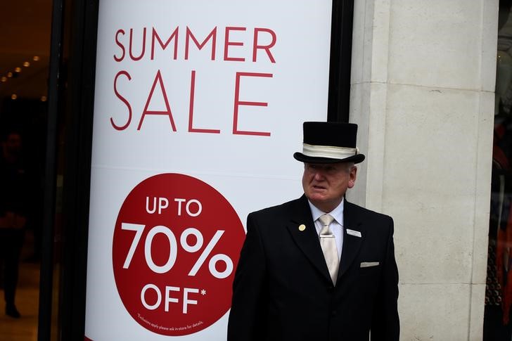 © Reuters. A concierge stands outside a shop that is having a summer sale in Dublin