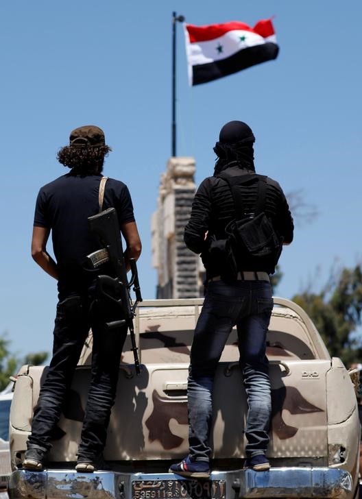 © Reuters. Rebel fighters stand on the back of a truck in Quneitra