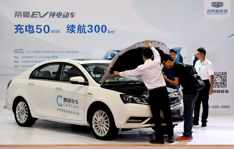 © Reuters. Men look at an electric vehicle of Caocao Zhuanche at a new energy vehicle (NEV) trade fair in Zhengzhou