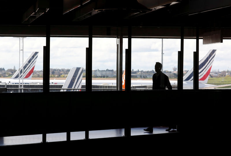 © Reuters. FILE PHOTO: A passenger walks as Air France planes are parked on the tarmac at Orly Airport near Paris as Air France pilots, cabin and ground crews unions call for a strike over salaries