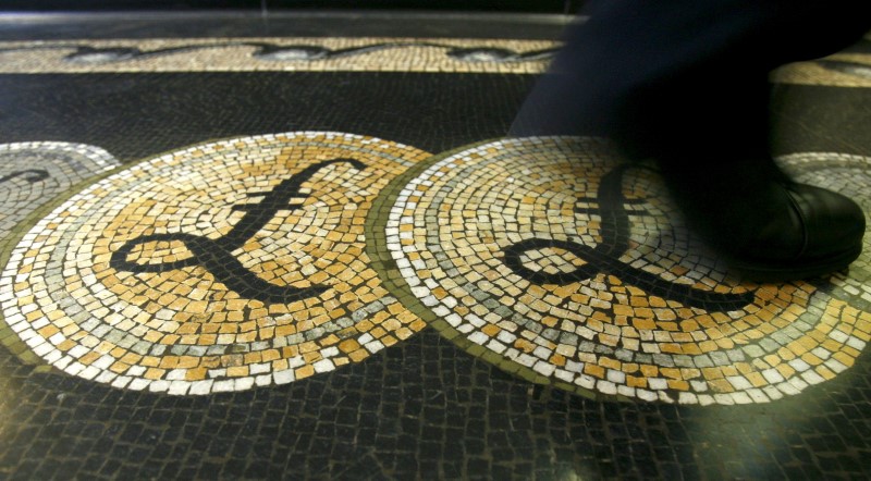 © Reuters. FILE PHOTO: File photograph shows an employee walking over a mosaic depicting pound sterling symbols on the floor of the front hall of the Bank of England in London