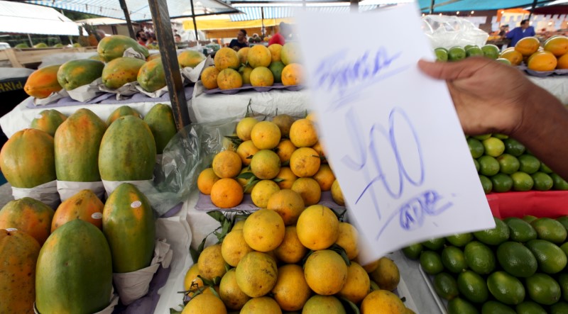 © Reuters. Vendedor segura placa com preço de fruta em feira de São Paulo