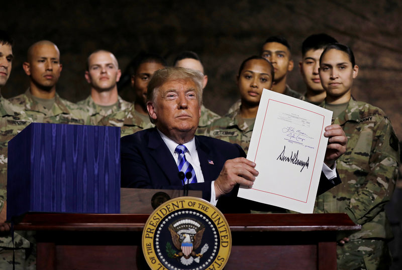 © Reuters. U.S. President Trump holds up the National Defense Authorization Act after signing it in front of soldiers at Fort Drum, New York