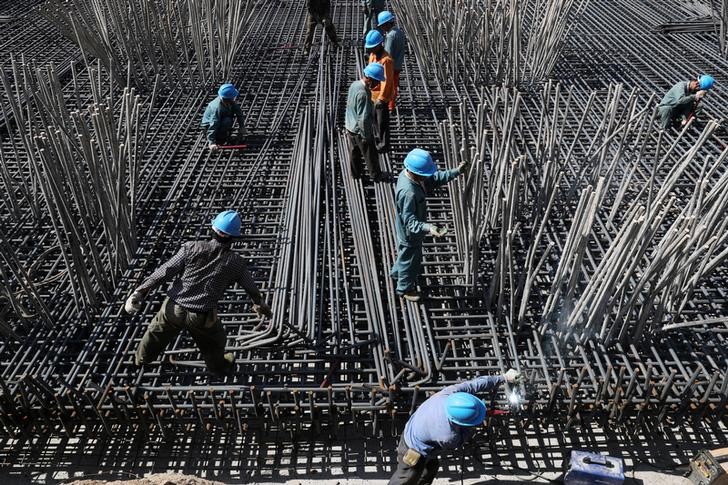 © Reuters. FILE PHOTO: Workers are seen amid steel bars at a construction site of a highway in Zhaotong